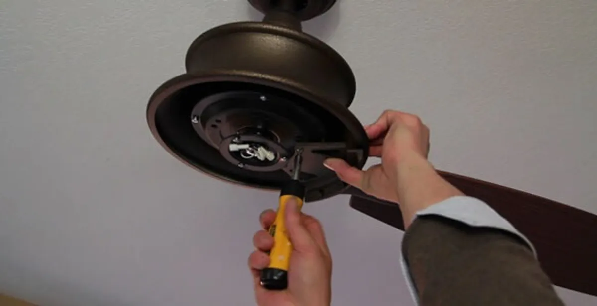 Electrician installing ceiling fan mounting bracket and fixture in Dallas, TX