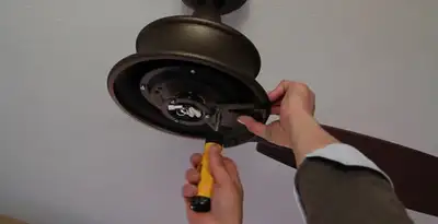 Electrician installing ceiling fan mounting bracket and fixture in Dallas, TX