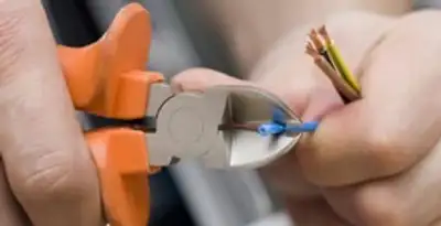 licensed electrician performing precise wire cutting and preparation during electrical service in Dallas, TX