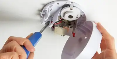 Certified technician wiring smoke detector during installation in Dallas, TX